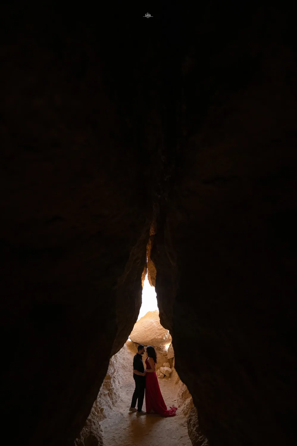 Couple in a cave lit by a shaft of daylight